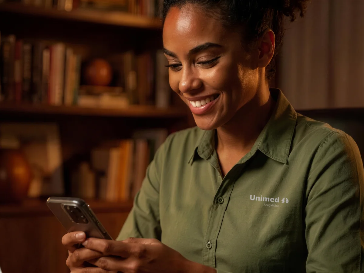Mulher sorrindo enquanto usa o celular em casa