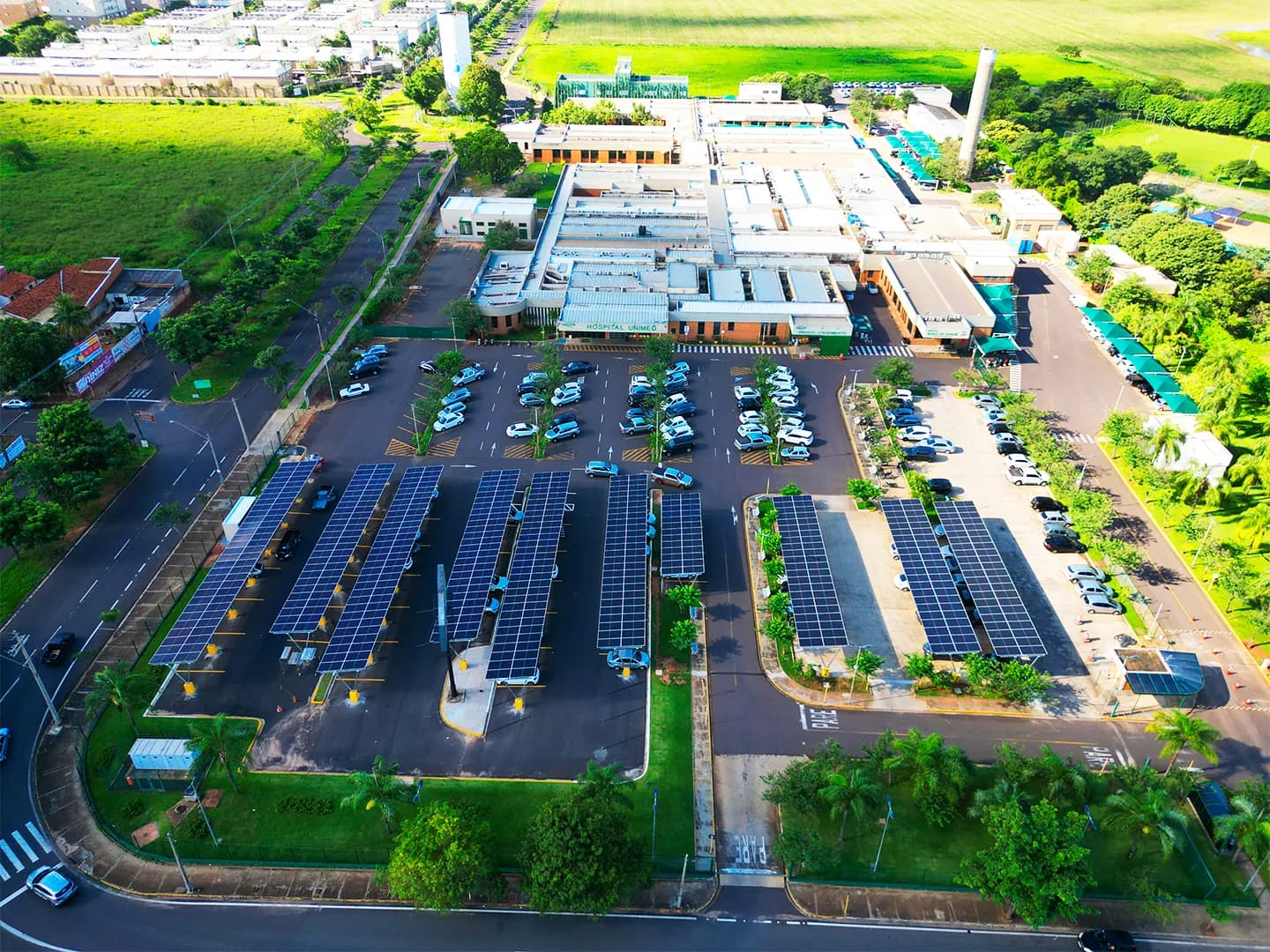 Vista aérea do complexo da Unimed Araçatuba, com o estacionamento coberto por painéis solares